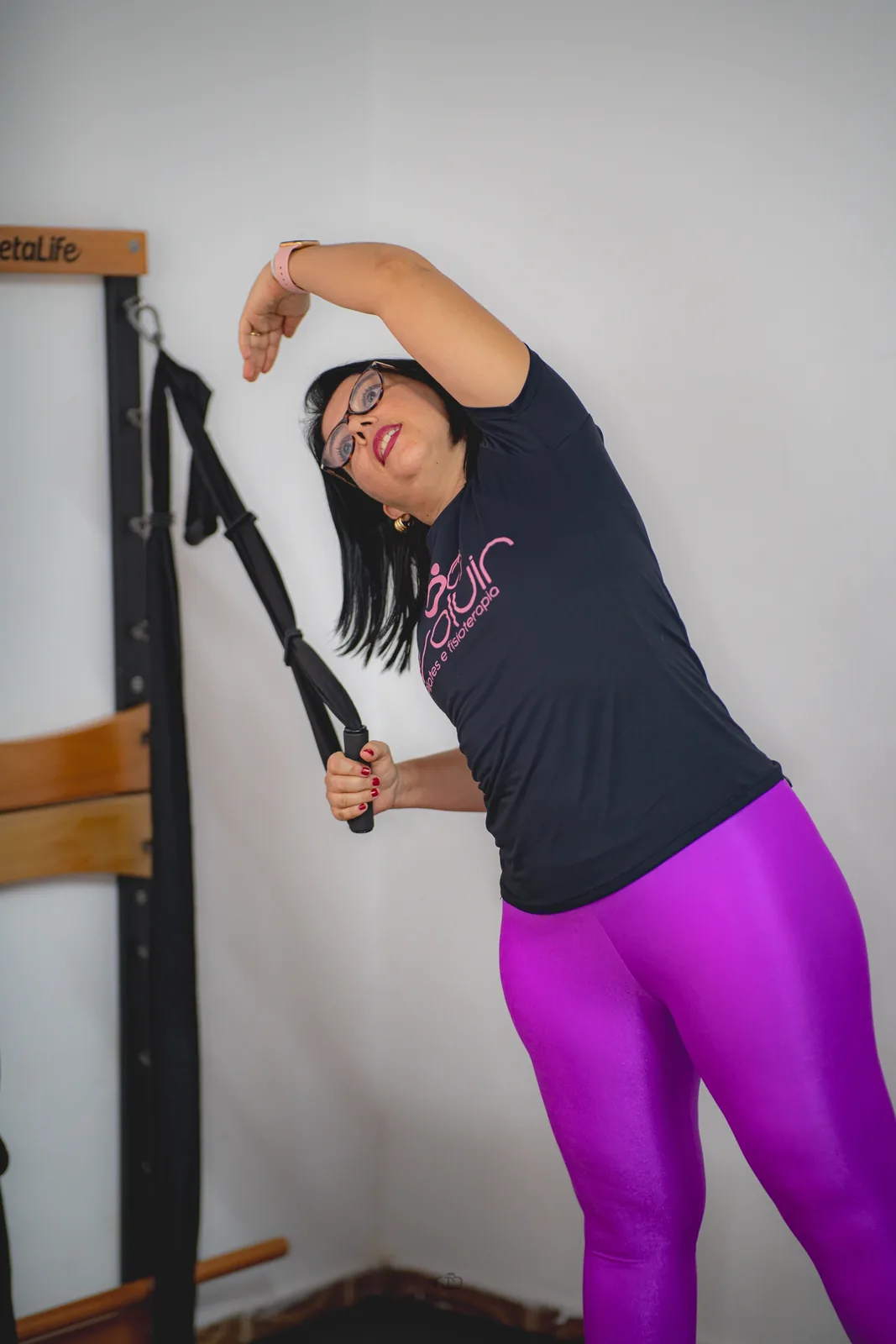 Aluna realiza um alongamento lateral com aparelho de Pilates na Evoluir.