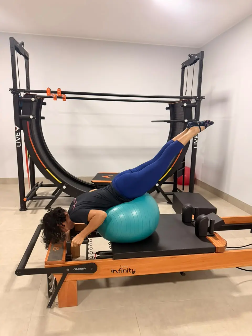 Aluna utiliza equipamentos de Pilates em um estúdio da Evoluir, com o V12 ao fundo.